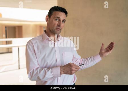 Homme d'affaires donnant la présentation devant le mur au bureau Banque D'Images