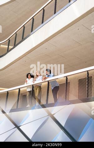 Les gens d'affaires multiraciaux penchent sur des rampes dans le couloir Banque D'Images