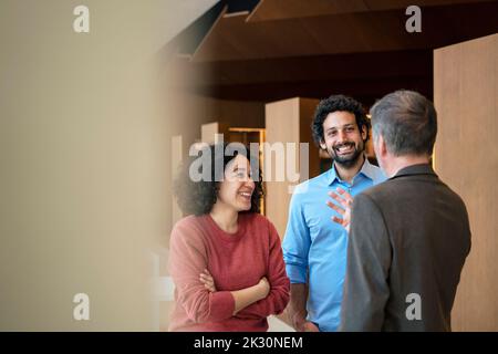 Heureux collègues multiraciaux discutant au bureau Banque D'Images