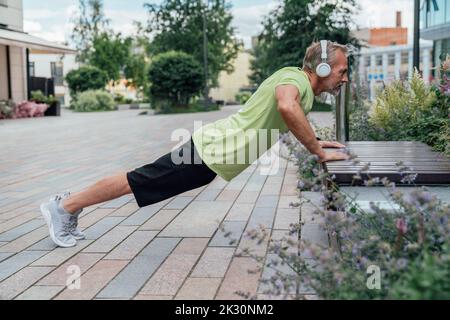 Mature man doing push-ups on bench Stock Photo