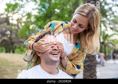 Femme souriante couvrant les yeux de l'ami au parc Banque D'Images