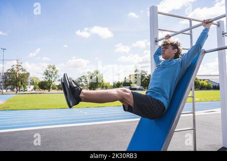 Jeune sportif pratiquant sur la barre horizontale Banque D'Images