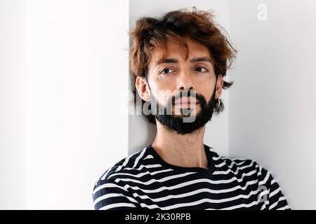 Homme barbu bien pensé devant le mur Banque D'Images