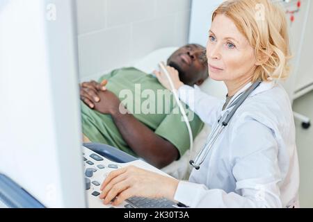 Médecin avec cheveux blonds faisant l'échographie du patient en clinique Banque D'Images