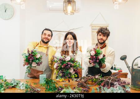 Fleuristes souriants tenant des bouquets debout à la boutique florale Banque D'Images