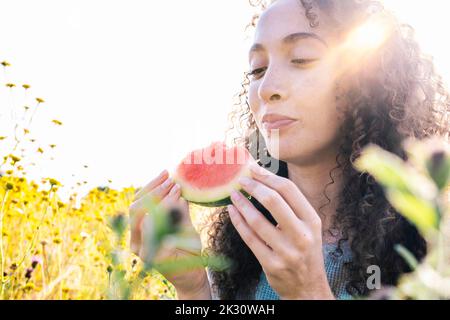 Femme souriante avec une tranche de pastèque dans le parc par beau temps Banque D'Images