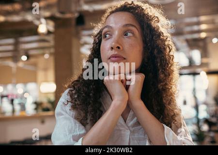 Femme d'affaires attentionnés assise avec les mains sur le menton au bureau Banque D'Images