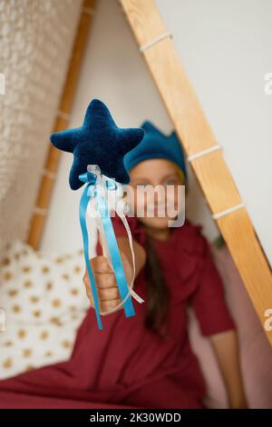 Girl showing magic wand sitting in tent Stock Photo