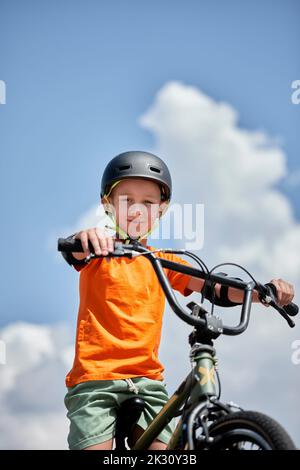 Boy wearing helmet sitting on BMX bike Stock Photo