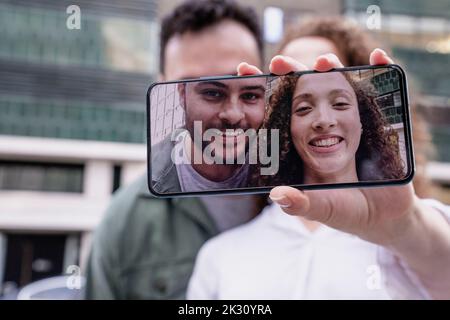 Des amis souriants prennent leur selfie sur un smartphone Banque D'Images