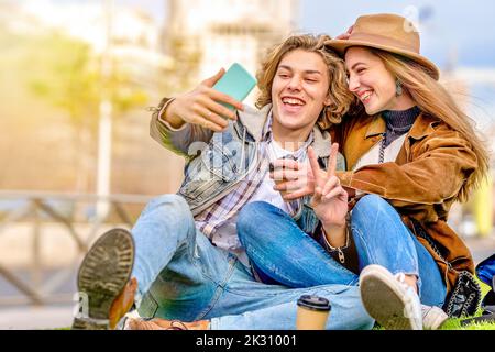 Man showing peace sign taking selfie with friend through smart phone Stock Photo