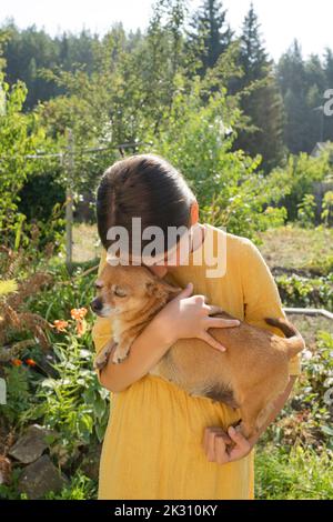 Jeune fille embrassant le chien dans le jardin le jour ensoleillé Banque D'Images