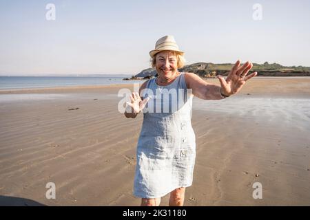 Cheerful senior woman dancing and having fun on beach at vacation Banque D'Images