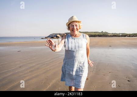 Bonne femme âgée dansant et s'amusant à la plage Banque D'Images