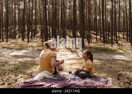 Mature woman and girl enjoying picnic in forest Banque D'Images