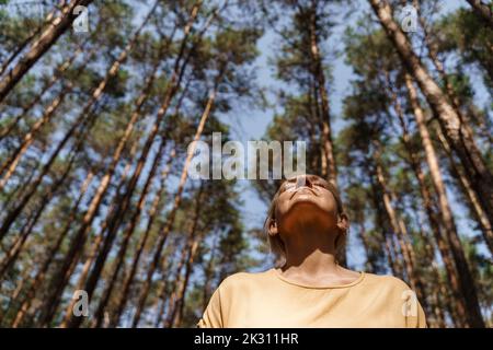 Femme mûre appréciant la nature devant les arbres à la forêt Banque D'Images