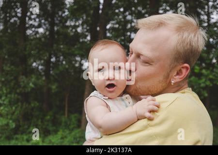 Père embrassant bébé fille mignon dans le parc