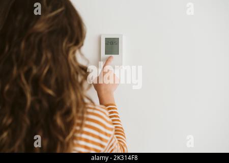 Femme réglant la commande de chauffage au mur Banque D'Images