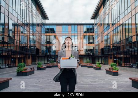 Femme d'affaires avec boîte à l'extérieur du bâtiment de bureau Banque D'Images