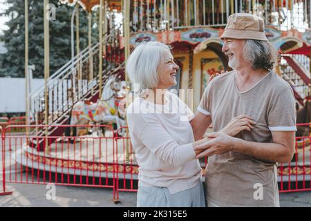 Bonne femme en train de profiter avec l'homme devant le carrousel Banque D'Images