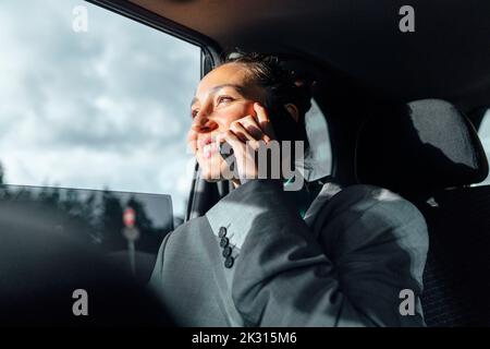Bonne femme d'affaires parlant sur un smartphone assis en voiture Banque D'Images