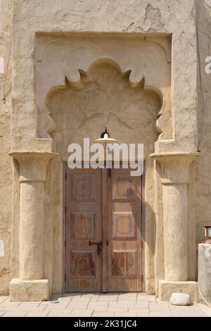 Entrée vintage à la maison orientale avec des portes fermées en bois usées décorées avec des colonnes et une arche en grès sculptées. Banque D'Images