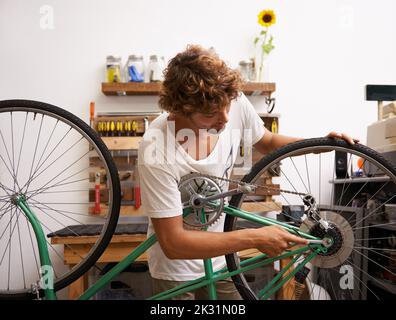 Donner un tuneup à l'ancien vélo. Un jeune réparateur de vélo confiant. Banque D'Images