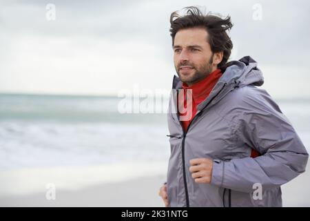 Une course matinale sur la plage. Un beau jeune homme qui court sur la plage. Banque D'Images