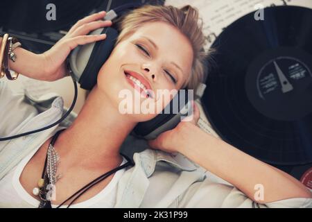 La musique est ce à quoi les sentiments semblent ressembler. Une belle jeune femme souriant tout en écoutant de la musique. Banque D'Images