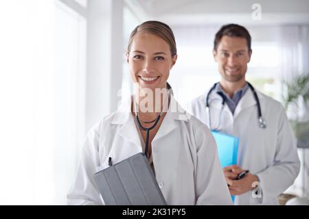 Partenaires en santé. Portrait de deux jeunes médecins debout dans un couloir d'hôpital. Banque D'Images