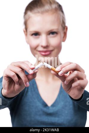 Je choisis la santé. Un court studio photo d'une belle jeune femme qui casse une cigarette en deux. Banque D'Images