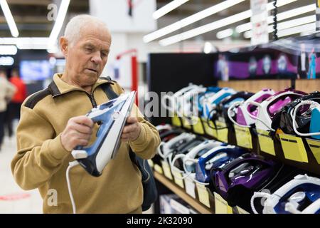 sénior homme retraité achetant du fer dans la salle d'exposition du magasin d'appareils électriques Banque D'Images