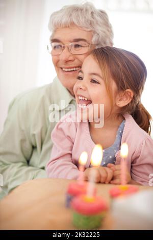 Elle fait les meilleurs cupcakes. Portrait d'une grand-mère heureuse célébrant un anniversaire avec sa petite-fille à la maison. Banque D'Images