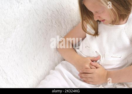 Une adolescente presse ses mains sur son ventre dans la douleur. Concept médical. Banque D'Images