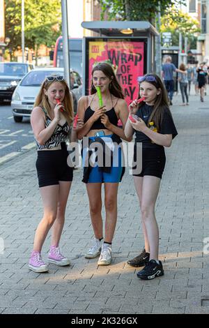 Jeunes filles mangeant de la glace dans la rue , Derry , Irlande du Nord . Banque D'Images