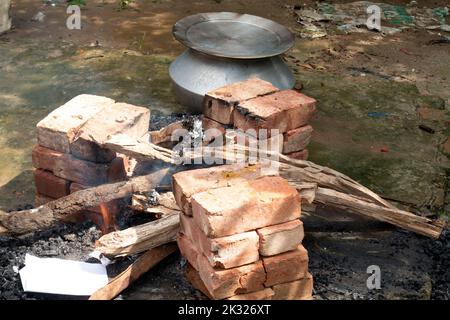 La cuisine biryani dans un village partie sur un four temporaire en brique. Cuisine extérieure pour beaucoup de personnes dans une grande poêle en aluminium au feu de bois. Banque D'Images