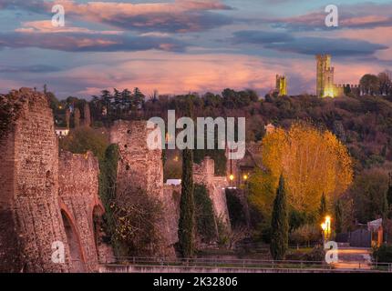 Pont médiéval au coucher du soleil sur le fleuve Mincio à Borghetto, entre Vérone et Mantoue, Italie. Un château sur la colline domine la vallée. Banque D'Images