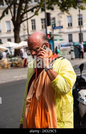 Paris, France. Août 2022. Un lièvre Krishna suiveur sur son téléphone portable. Photo de haute qualité Banque D'Images