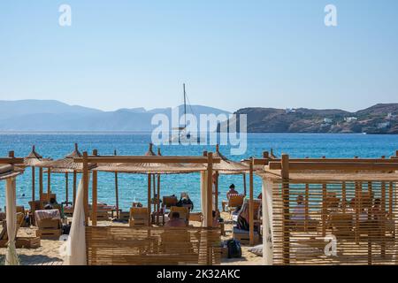 IOS, Grèce - 13 septembre 2022 : vue des touristes appréciant la belle plage de Mylopotas dans iOS Grèce et un voilier au loin Banque D'Images