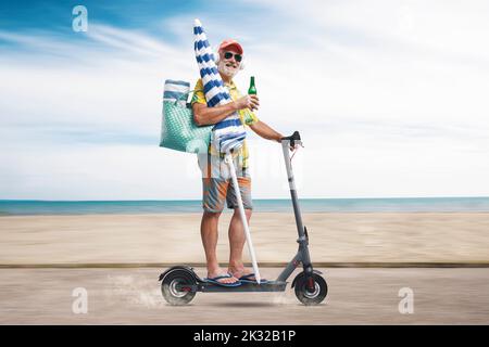 Heureux touriste senior à cheval un scooter électrique écologique et aller à la plage, la mer et la plage en arrière-plan Banque D'Images