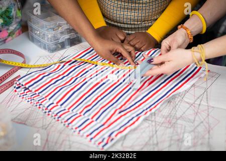 Les concepteurs de vêtements mesurent le tissu de la tailleur sur une table de tailleur. Banque D'Images