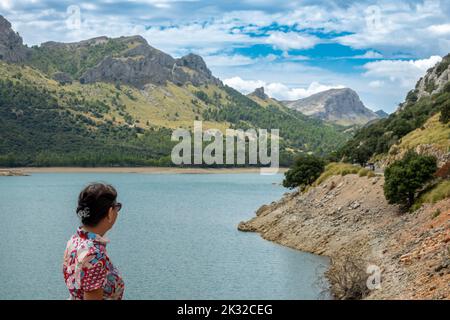 Femme de 50 ans avec une robe fleurie et des lunettes de soleil en admirant la beauté du réservoir Gorg Blau à Majorque (Espagne) un matin d'été Banque D'Images