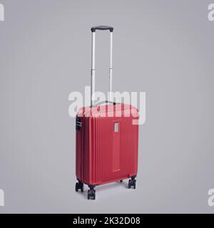 Valise à roulettes rouge élégante avec quatre roues sur fond gris, concept voyage et tourisme Banque D'Images