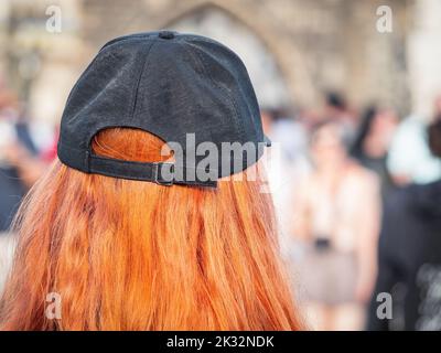 Vue arrière d'une femme à tête rouge portant un chapeau noir. Banque D'Images