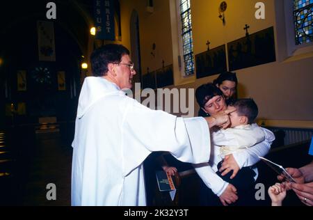 St Joseph's Church Roehampton Priest onction Baby with Oil of Chrism at font parents & Godparents Banque D'Images