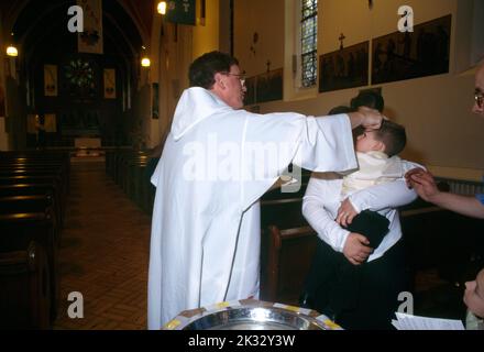 St Joseph's Church Roehampton Priest onction Baby with Oil of Chrism at font parents & Godparents Banque D'Images