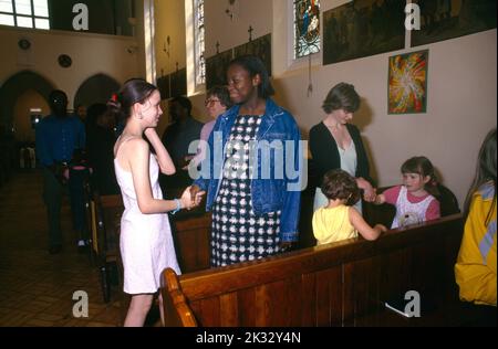 La Congrégation entre la main après la Communion signe de la paix Église Saint-Joseph Roehampton Londres Angleterre Banque D'Images