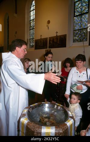 Parents renouvelant leurs promesses avec des priest et des parrains à l'église catholique St Joseph Roehampton, Londres, Angleterre Banque D'Images