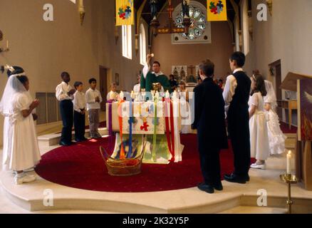 Prêtre à l'autel exécutant l'Eucharistie à la première communion de l'église St Joseph Roehampton Londres Angleterre Banque D'Images