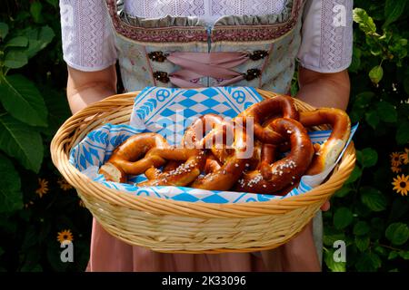 Une femme dans une belle robe traditionnelle bavaroise de dirndl tenant un panier de bretzels (Brezeln) à l'Oktoberfest bavarois (Munich, Bavière) Banque D'Images